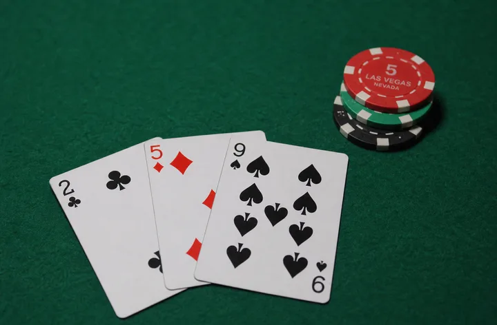 Scattered low Teen Patti High Card hand on green felt with modest gold practice chips